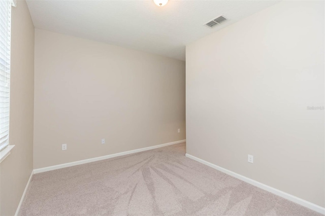 unfurnished room with light carpet, baseboards, and visible vents