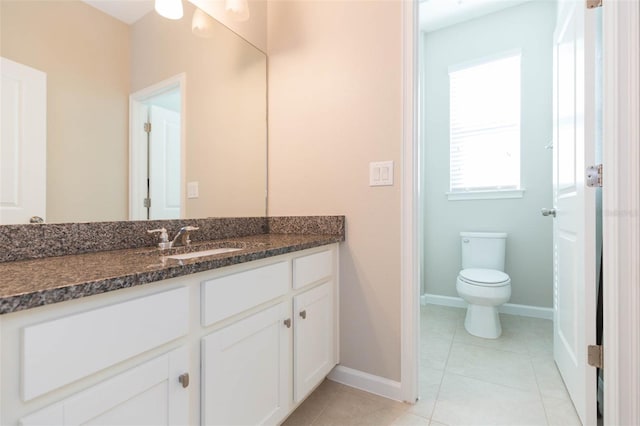 bathroom with tile patterned flooring, baseboards, vanity, and toilet