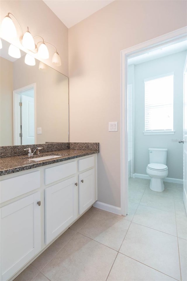 bathroom featuring toilet, vanity, baseboards, and tile patterned floors