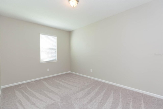 empty room featuring light colored carpet and baseboards