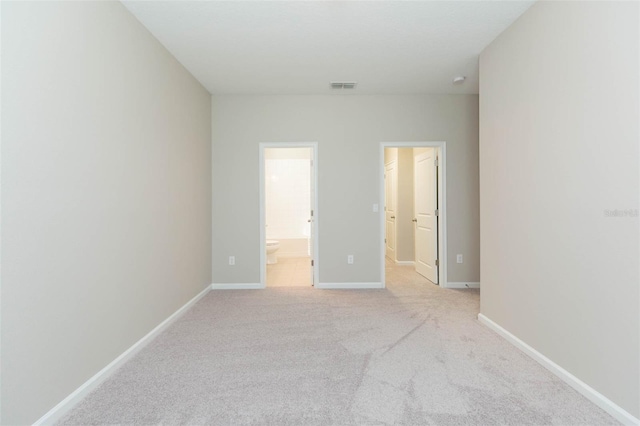 unfurnished bedroom with light carpet, ensuite bath, visible vents, and baseboards