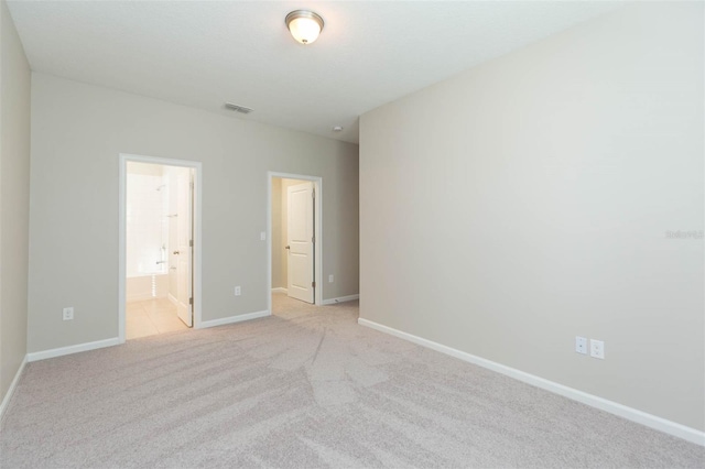 unfurnished bedroom with light colored carpet, visible vents, connected bathroom, and baseboards