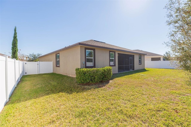 rear view of property with a fenced backyard, a lawn, and stucco siding