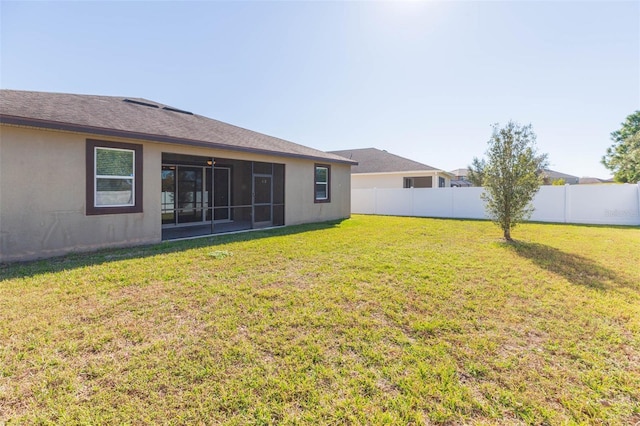 back of property featuring a sunroom, fence, a lawn, and stucco siding