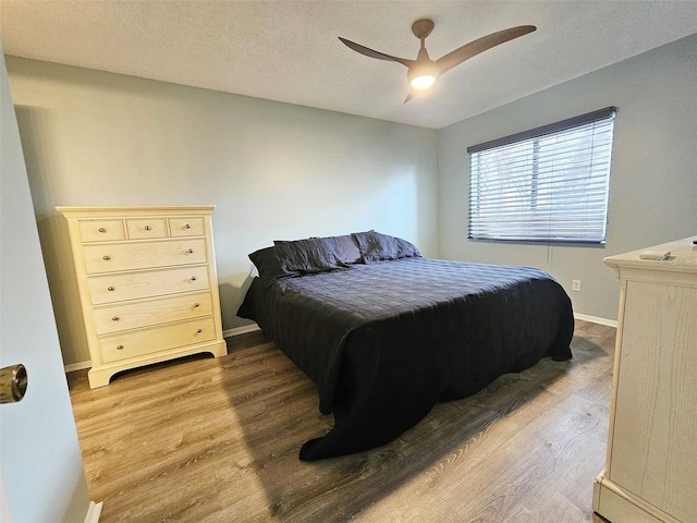 bedroom featuring hardwood / wood-style flooring, a textured ceiling, and ceiling fan