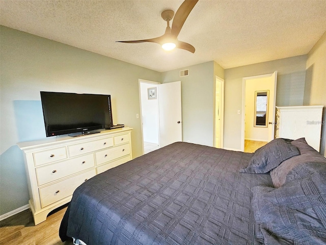 bedroom featuring a textured ceiling, ceiling fan, and light wood-type flooring