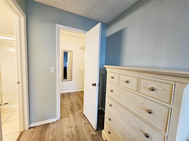 corridor with light hardwood / wood-style floors and a textured ceiling