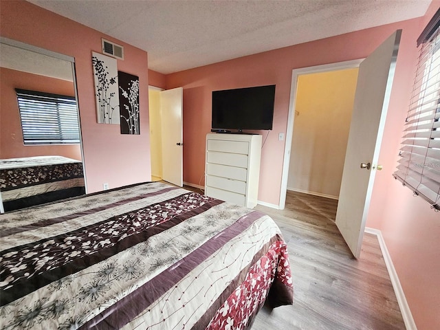 bedroom with a textured ceiling and light hardwood / wood-style floors