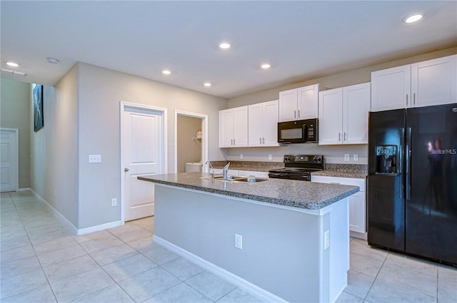 kitchen with light tile patterned flooring, sink, white cabinets, black appliances, and a center island with sink