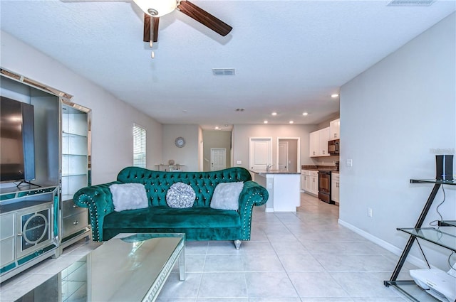 tiled living room featuring ceiling fan, sink, and a textured ceiling