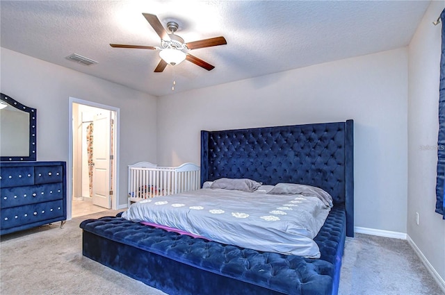 carpeted bedroom with a textured ceiling, ceiling fan, and ensuite bath