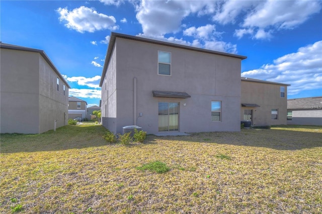 rear view of property featuring central AC and a lawn