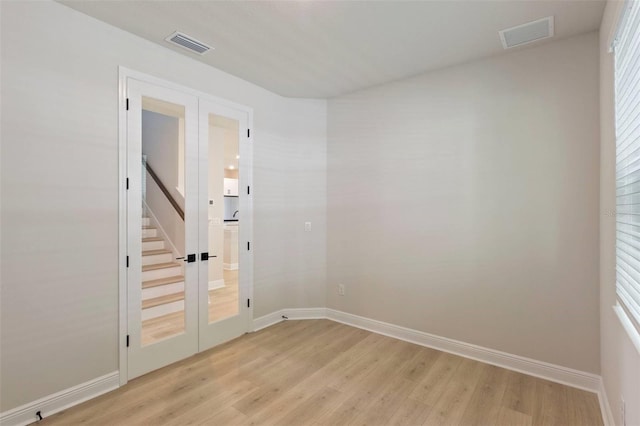 empty room featuring visible vents, french doors, baseboards, and light wood-style floors