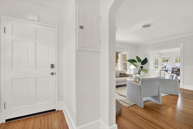 interior space with wood-type flooring, ornamental molding, and electric panel