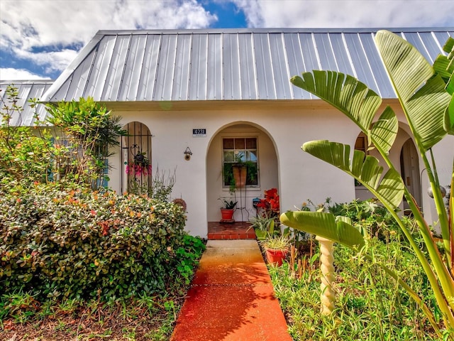 entrance to property featuring covered porch, metal roof, and stucco siding