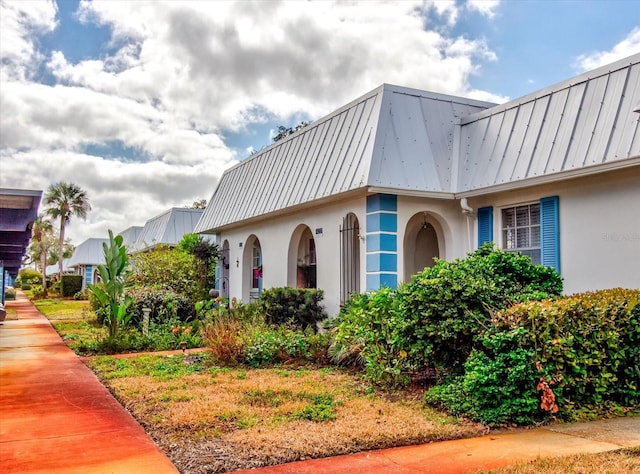 view of side of property featuring metal roof and stucco siding