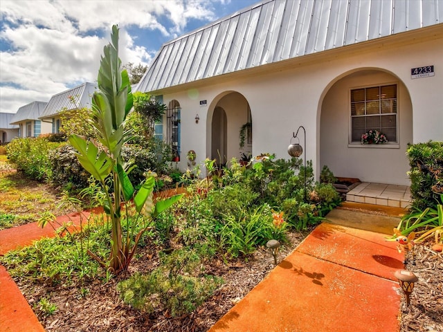 doorway to property featuring stucco siding and mansard roof