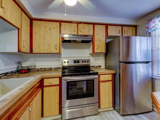 kitchen featuring light wood finished floors, ceiling fan, stainless steel appliances, crown molding, and under cabinet range hood