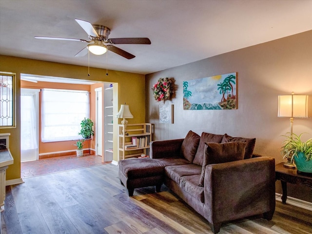 living room featuring baseboards, a ceiling fan, and wood finished floors