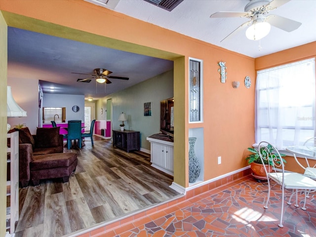 interior space with ceiling fan, baseboards, and wood finished floors