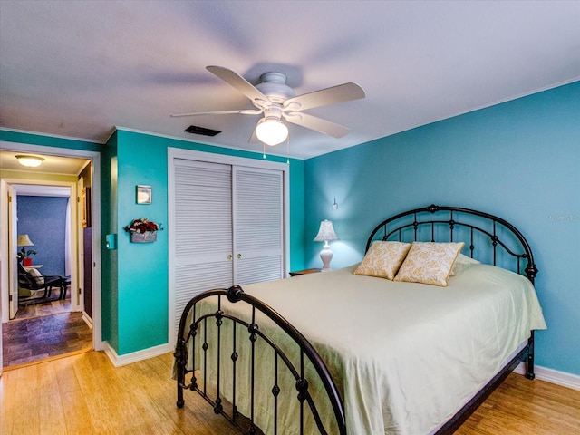 bedroom with a ceiling fan, a closet, baseboards, and wood finished floors