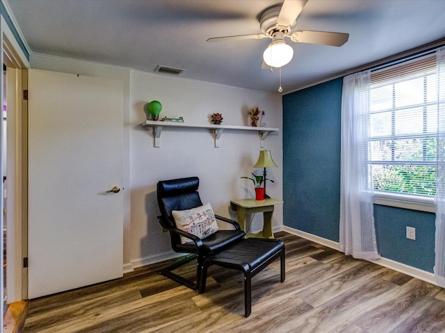 living area featuring a ceiling fan, baseboards, visible vents, and wood finished floors