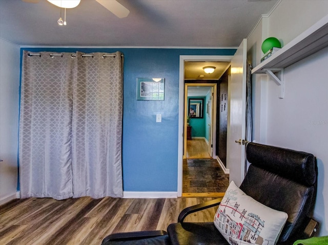 sitting room featuring a ceiling fan, baseboards, ornamental molding, and wood finished floors