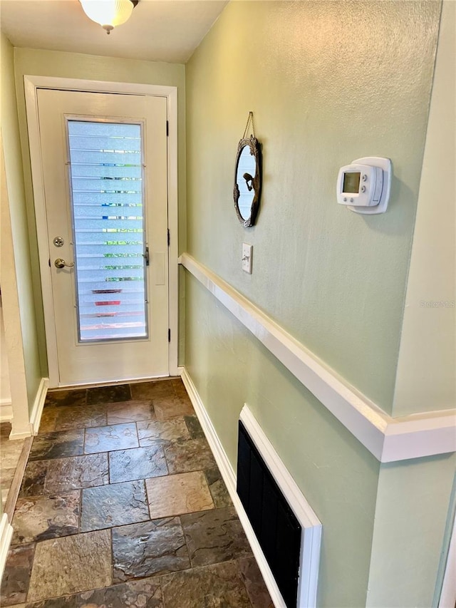 doorway to outside featuring baseboards, visible vents, and stone tile floors