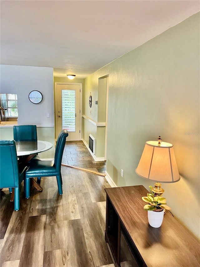 dining area with wood finished floors, visible vents, and baseboards