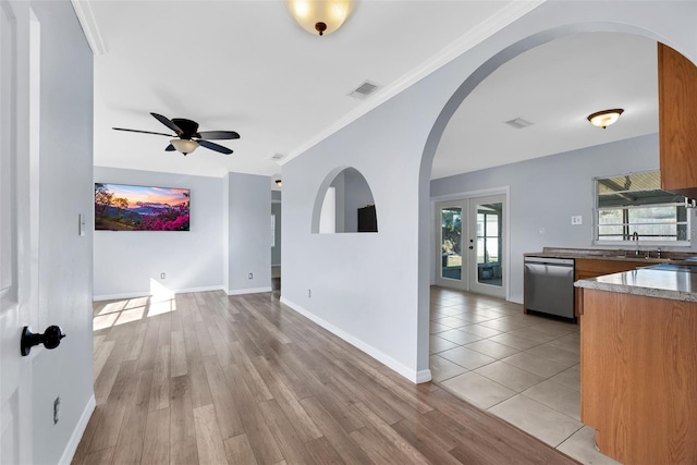 unfurnished living room featuring crown molding, ceiling fan, light hardwood / wood-style floors, and french doors