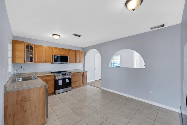 kitchen featuring light stone counters, appliances with stainless steel finishes, sink, and light tile patterned floors