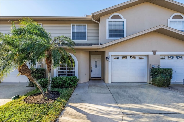 view of property featuring stucco siding, concrete driveway, and an attached garage