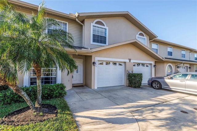 multi unit property with a garage, driveway, and stucco siding