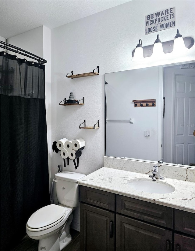 bathroom with vanity, toilet, and a textured ceiling