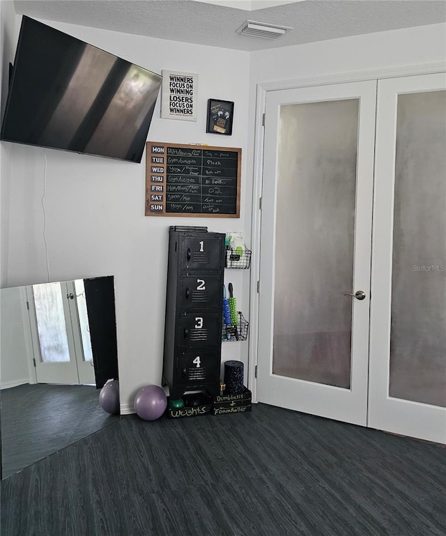 interior space with dark hardwood / wood-style floors, a textured ceiling, and french doors