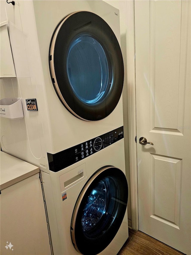 clothes washing area featuring stacked washer and clothes dryer and dark hardwood / wood-style floors