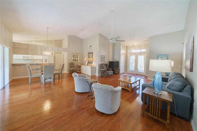 living room featuring ceiling fan, high vaulted ceiling, wood finished floors, baseboards, and french doors