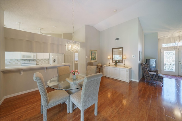 dining space with baseboards, visible vents, a chandelier, wood finished floors, and high vaulted ceiling