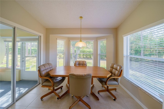 dining area featuring a wealth of natural light, lofted ceiling, a textured ceiling, and light tile patterned floors