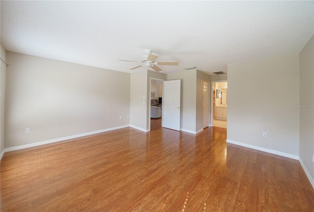 unfurnished room with ceiling fan, a textured ceiling, baseboards, and wood finished floors