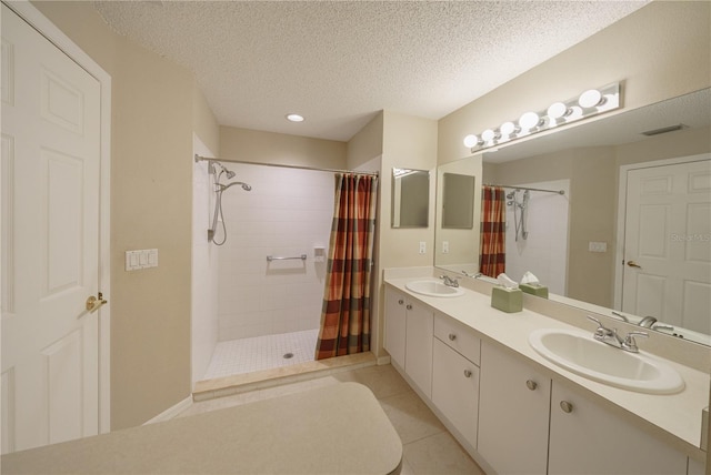 full bath with a textured ceiling, visible vents, a tile shower, and a sink