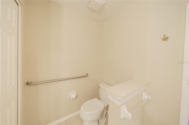 bathroom with toilet, tile patterned flooring, baseboards, and a textured ceiling