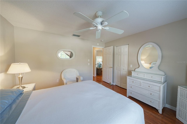 bedroom featuring baseboards, visible vents, a ceiling fan, dark wood-style flooring, and a textured ceiling