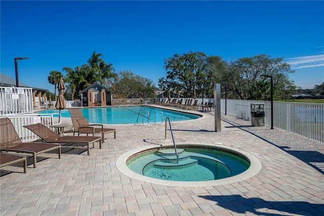 community pool featuring a patio, a hot tub, and fence