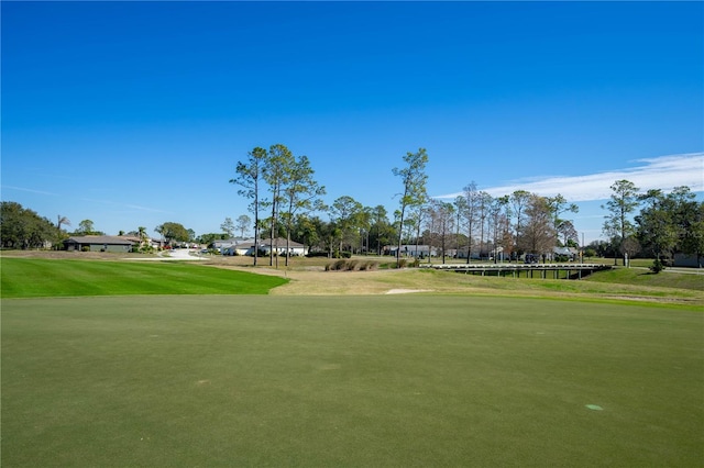 view of property's community with view of golf course and a lawn