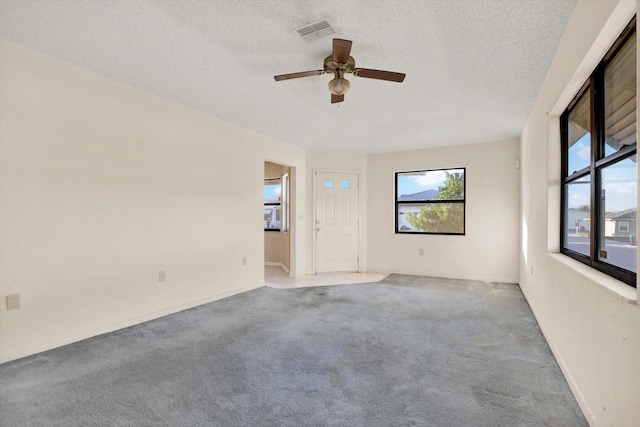 carpeted spare room with ceiling fan and a textured ceiling