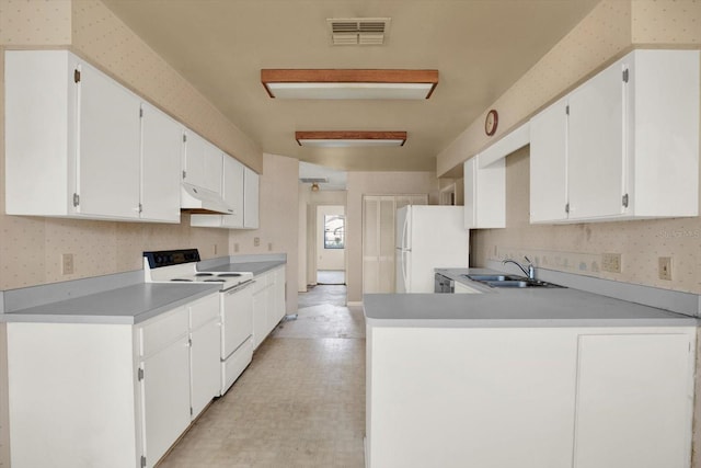 kitchen with white cabinetry, sink, white appliances, and kitchen peninsula