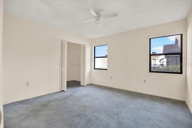 carpeted spare room featuring ceiling fan and a textured ceiling