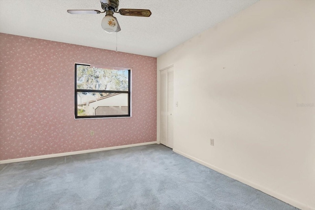 empty room featuring ceiling fan, a textured ceiling, and carpet flooring