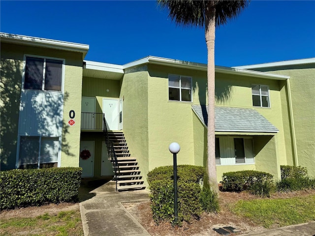 view of front facade with stairway and stucco siding